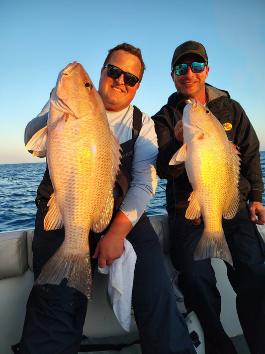 Two anglers holding large snapper fish on a boat, showcasing successful saltwater fishing with SnappaSlappa gear.