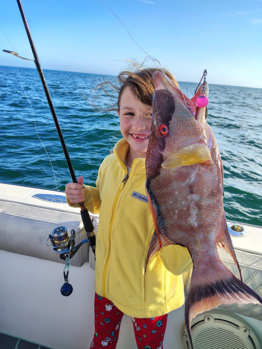 Young angler holding a hogfish caught with a pink jig head on a saltwater fishing trip